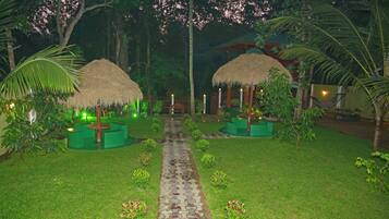 A pathway leading to thatched-roof structures surrounded by lush greenery.