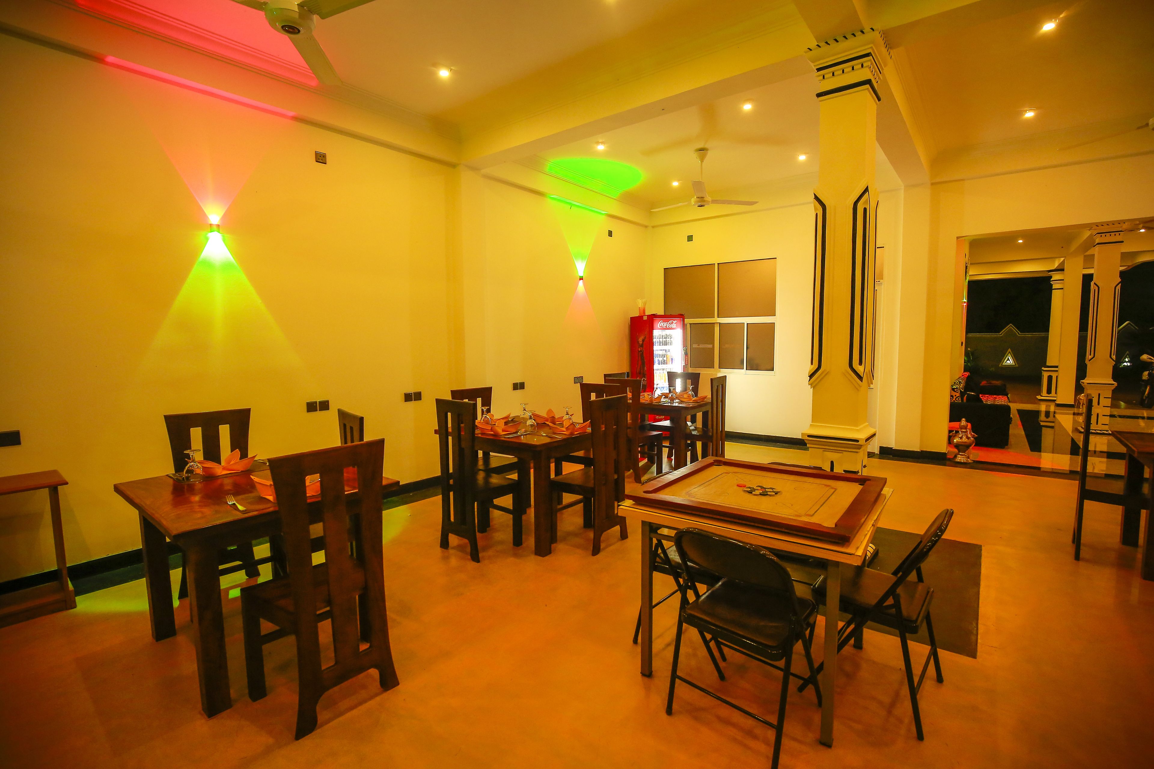 A dining area with wooden tables and chairs, a ceiling fan, and a vending machine.
