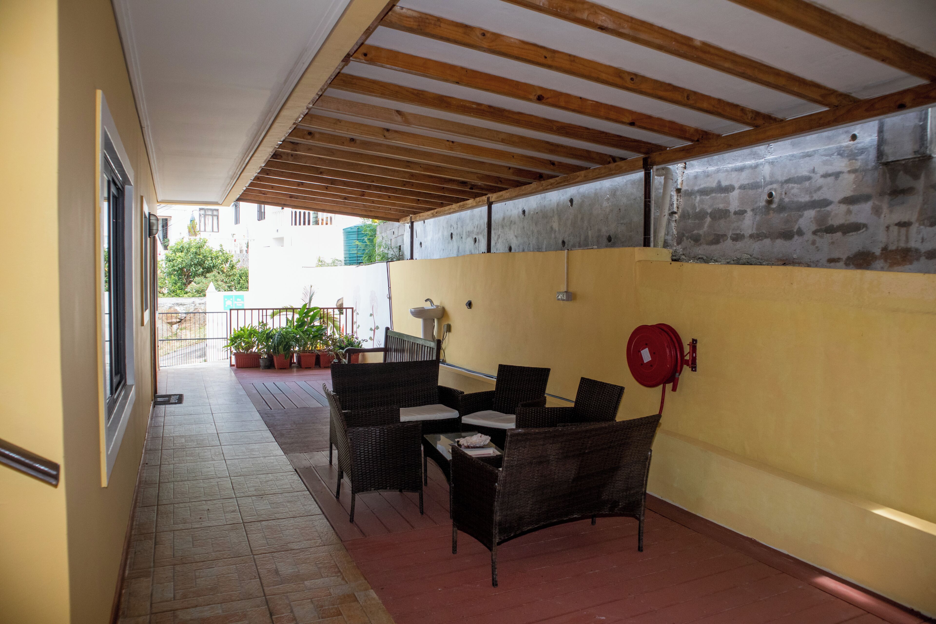 An outdoor patio with wicker furniture, a fire extinguisher, and potted plants.
