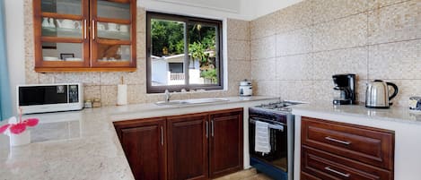 A modern kitchen with wooden cabinets, a microwave, a stove, and a coffee maker.