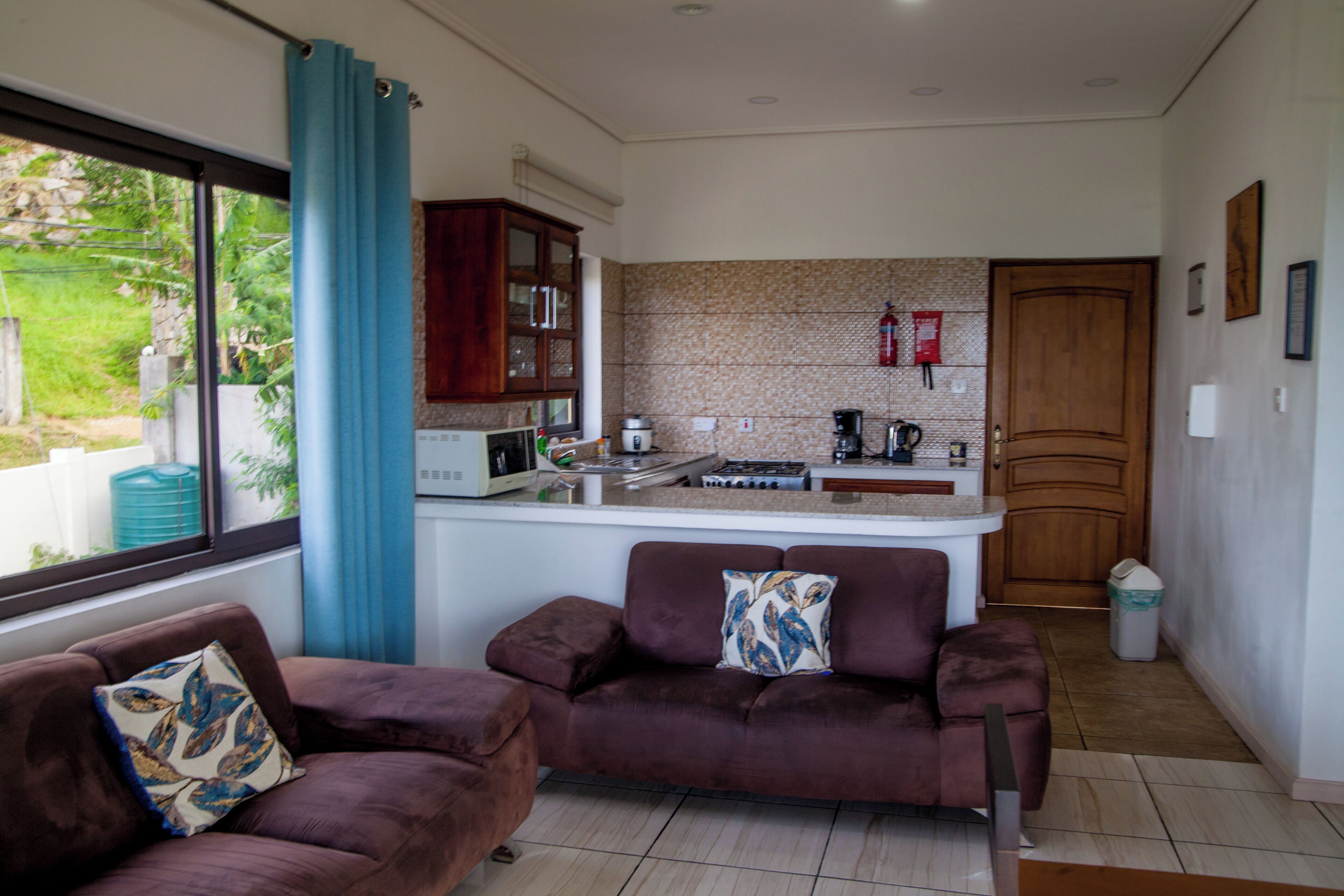 A compact living space with a kitchenette, a sofa, and a window with curtains.