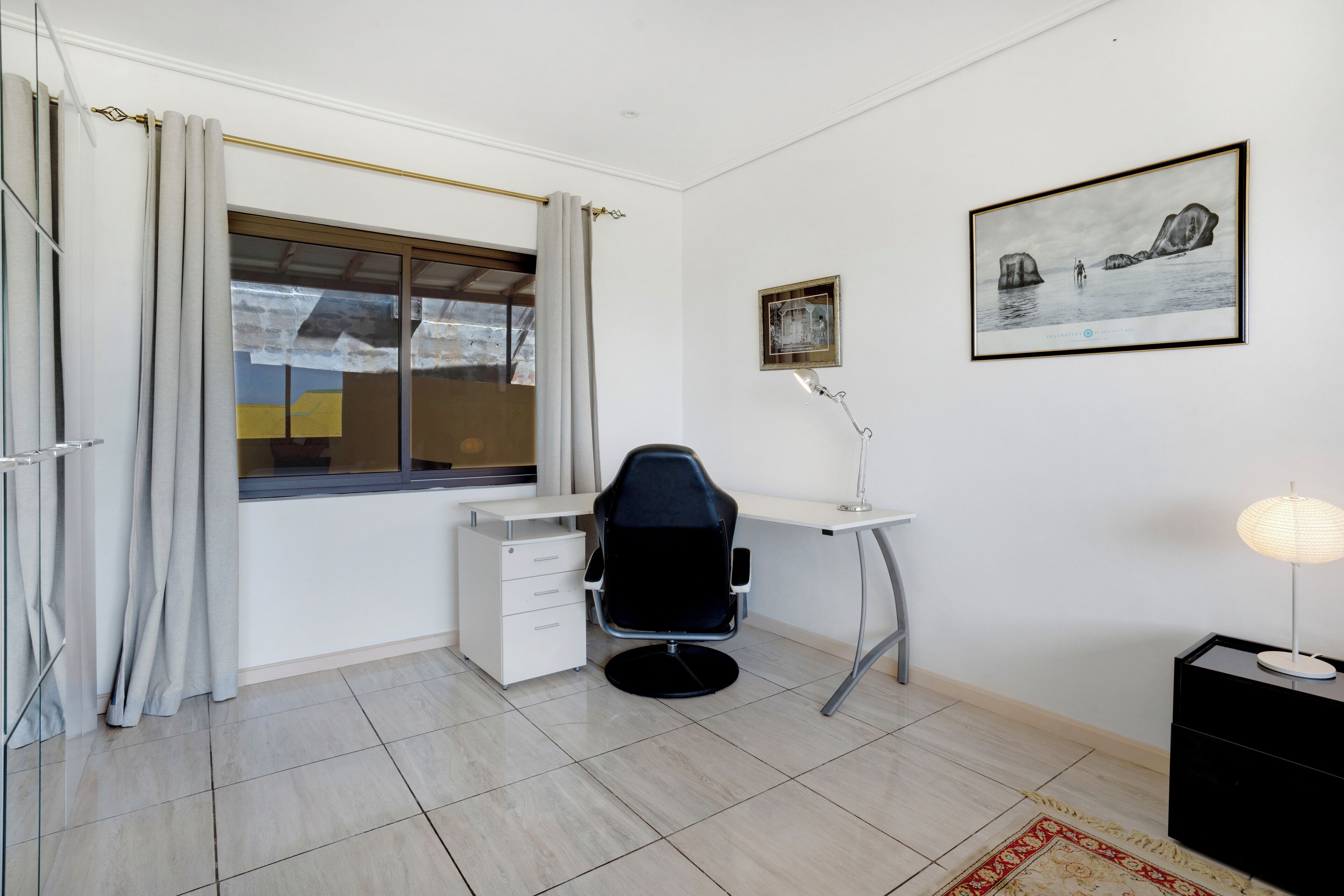 A modern office space with a desk, chair, and a framed artwork on the wall.