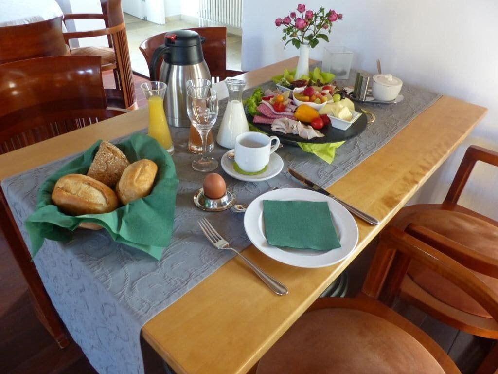 A breakfast setup with bread, eggs, fruit, and a coffee pot on a table.