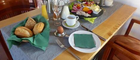 A breakfast setup with bread, eggs, fruit, and a coffee pot on a table.