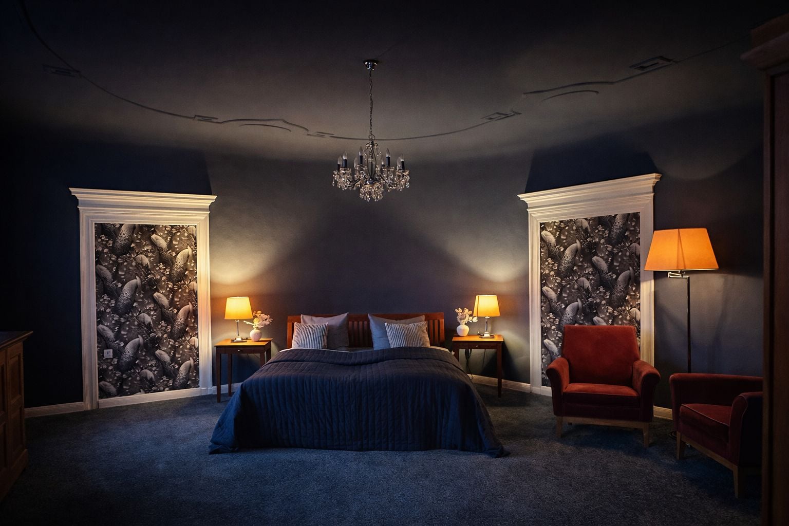 A bedroom with a large bed, two nightstands, a red armchair, a floor lamp, and a chandelier.