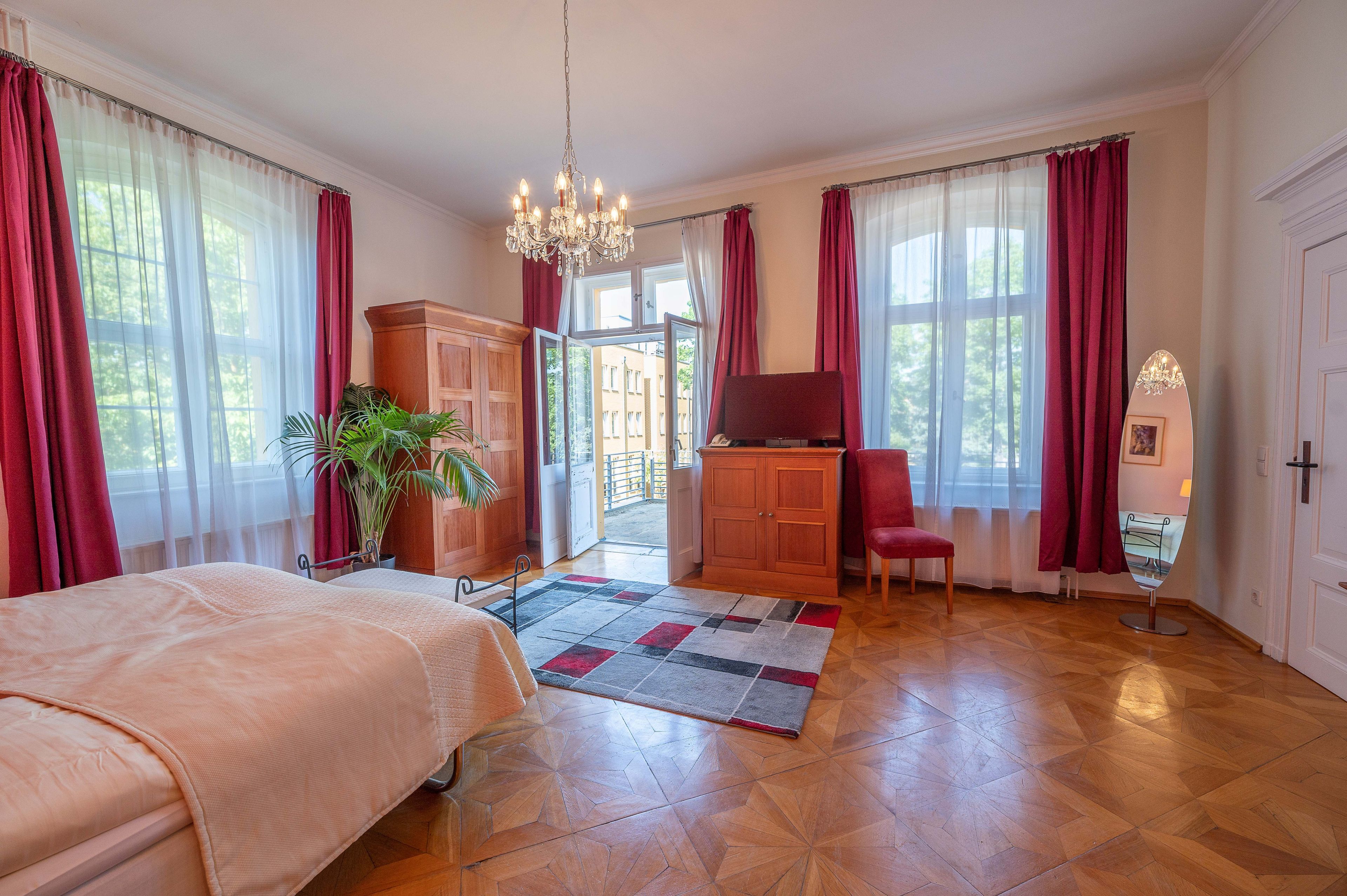 Une chambre d’hôtel avec un lit, un bureau, une chaise, une plante et une vue sur l’extérieur.