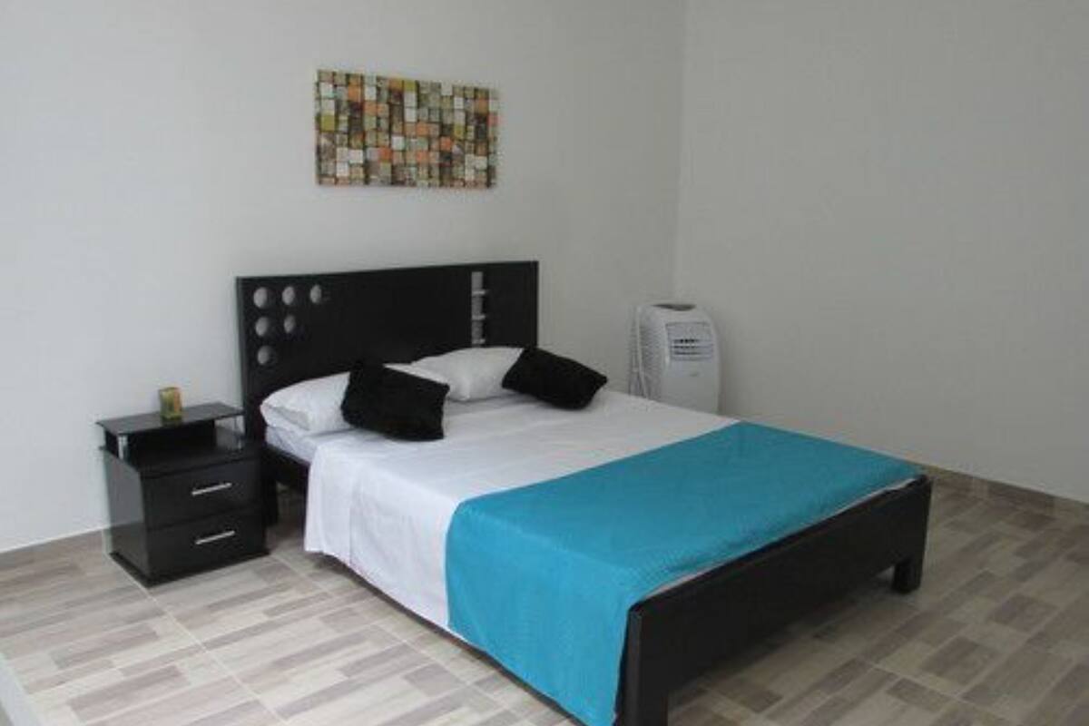 A neatly arranged bedroom with a bed, a bedside table, a heater, and a wall art piece.