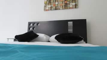 Una habitación de hotel moderna con una cama, un cabecero con cortes circulares y una obra de arte abstracta y colorida en la pared.