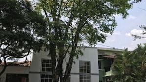 A two-story building with a white facade, multiple windows, and a visible door. - SGreen Duplex Apartments I (Cali)