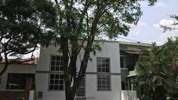 Un edificio de dos pisos con fachada blanca, varias ventanas y una puerta visible.