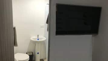 Un baño pequeño y privado con inodoro, lavamanos y cubo de basura.