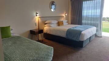 A hotel room with a large bed, a smaller bed, a nightstand, a wall-mounted mirror, and a window with curtains.
