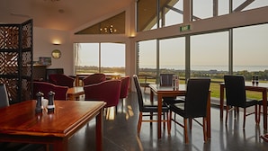 A spacious dining area with large windows offering a view of the landscape. - Koura Bay Resort (Hapuku)