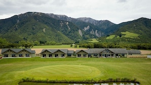 A golf course with a clubhouse featuring multiple rooms and a pond. - Koura Bay Resort (Hapuku)