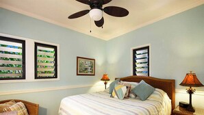 A bedroom with a bed, two nightstands, a chair, a ceiling fan, and a window with blinds.