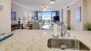 A modern kitchen with a large island, a built-in sink, and a dining area with a view.