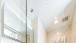 Ein modernes Badezimmer mit Duschkabine aus Glas, einem weißen Waschbecken und einer Toilette.