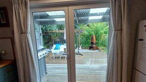 A kitchen with a sliding glass door leading to an outdoor patio area with a pool and garden. - The house for all seasons, occasions and ages. Perfect for families! (Greytown)