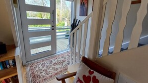 A staircase with a wooden handrail and a red heart-patterned cushion on a chair. - The house for all seasons, occasions and ages. Perfect for families! (Greytown)