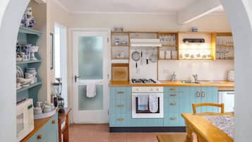 Una cocina con armarios azul verdoso, una estufa y varios utensilios de cocina.