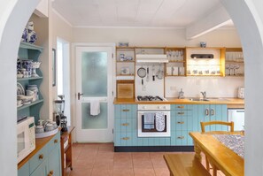 A kitchen with teal cabinets, a stove, and various kitchen utensils.