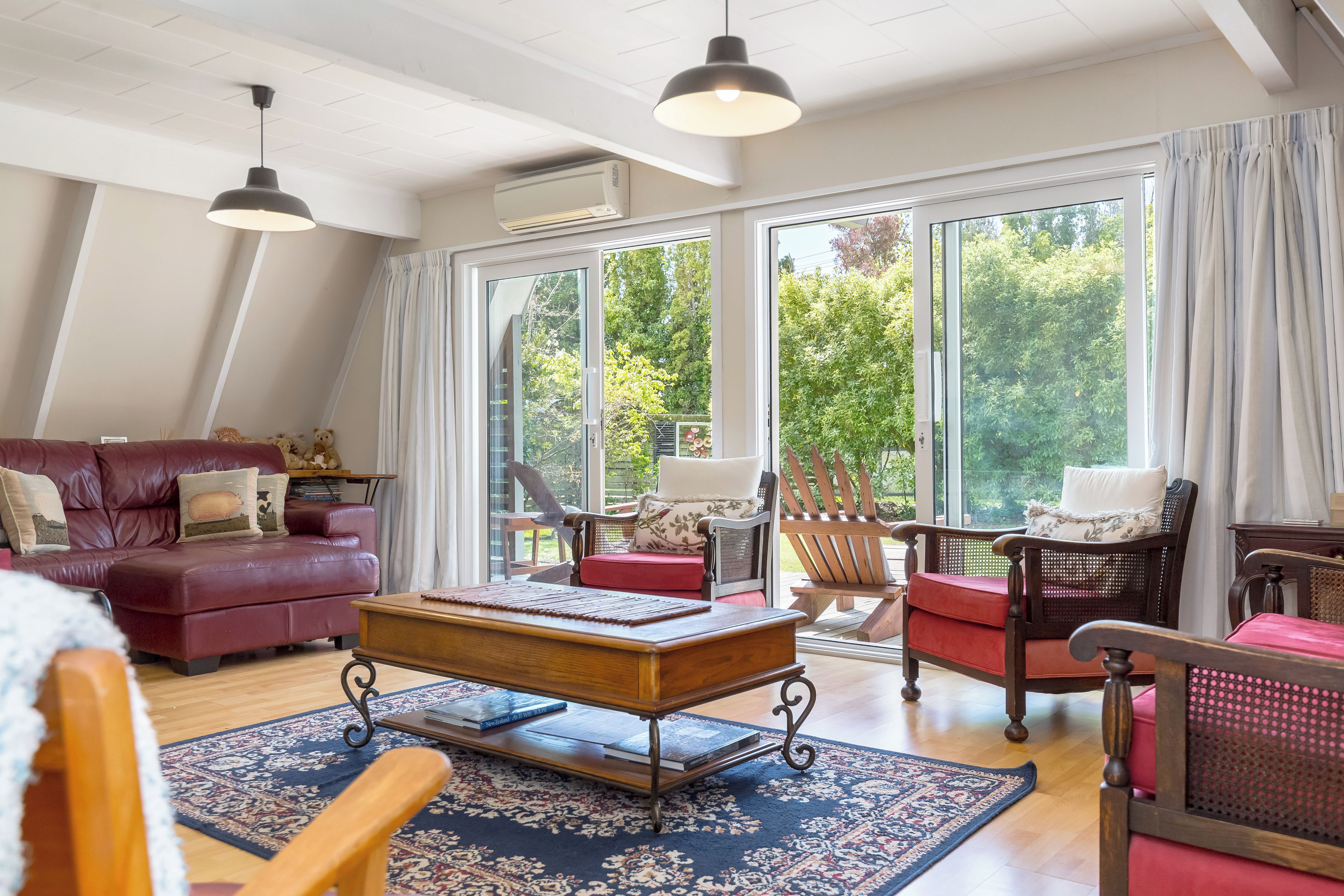 Een ruime woonkamer met een leren bank, een houten salontafel en een rode fauteuil.
