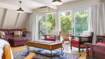 Een ruime woonkamer met een leren bank, een houten salontafel en een rode fauteuil.