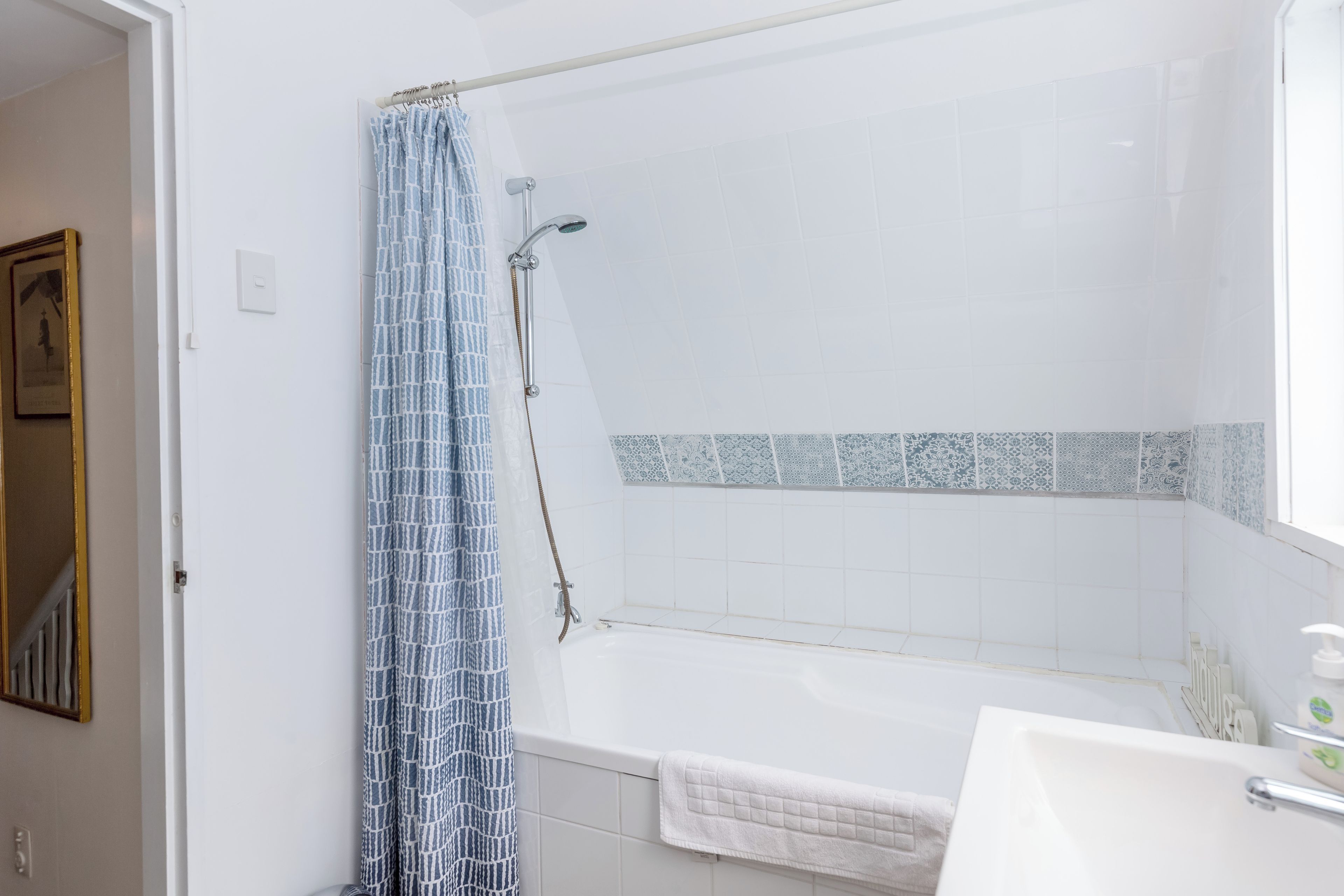 A bathroom with a bathtub, a shower curtain, and a towel rack.