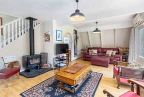 A living room with a fireplace, a television, a red sofa, and a wooden coffee table. - The house for all seasons, occasions and ages. Perfect for families! (Greytown)