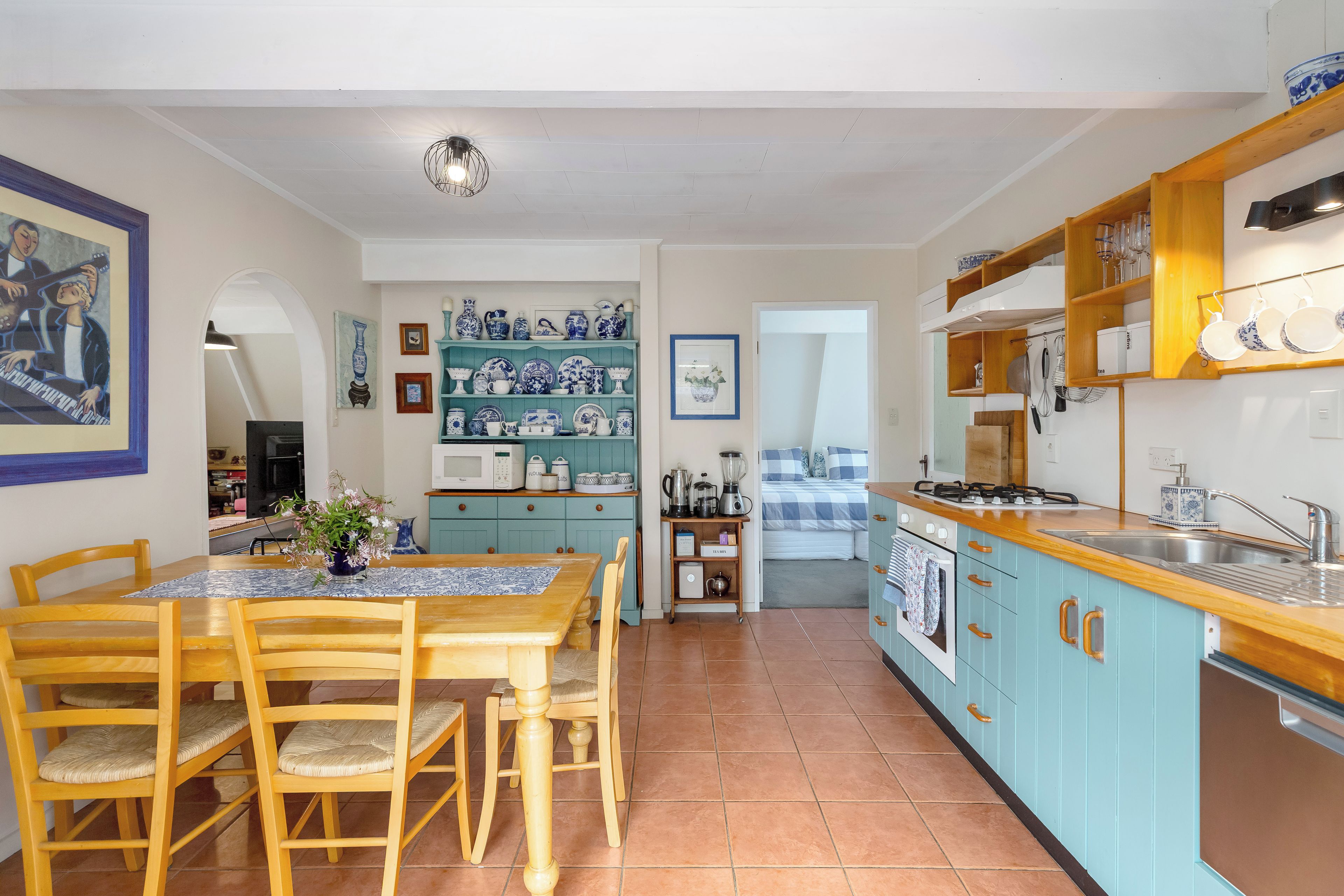 A kitchen with a dining area, featuring a table with chairs, a microwave, a stove, and various kitchen utensils.