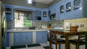 A kitchen with blue cabinets, a microwave, and a stove. - Bungalow on the Terrace Coral Gardens<br>Montego Bay (Montego Bay)