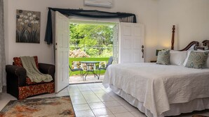 A bedroom with a bed, a chair, a table, and an open door leading to a balcony. - Bungalow on the Terrace Coral Gardens<br>Montego Bay (Montego Bay)