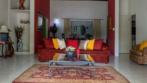 A living room with a red sofa, a coffee table, and a patterned rug. - Bungalow on the Terrace Coral Gardens<br>Montego Bay (Montego Bay)