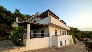 Ein modernes, zweistöckiges Haus mit überdachter Veranda, einer Treppe und einem gepflasterten Auffahrt.