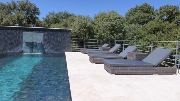 A swimming pool with a waterfall feature, surrounded by lounge chairs and a metal railing. - House / Villa - Gordes (Gordes)