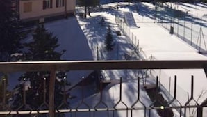 Un immeuble doté de nombreux balcons et dont le sol est recouvert de neige.