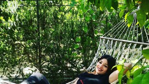 Iemand ontspant in een hangmat, omringd door groen.