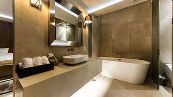 Un baño moderno con una bañera independiente, un espejo grande y un mostrador con lavabo y perchero.