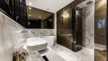 Un baño moderno con una bañera independiente, ducha con cerramiento de vidrio y piso de mármol.