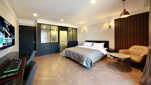 Une chambre d’hôtel moderne équipée d’un lit, d’un bureau avec un ordinateur, d’une chaise et d’un téléviseur.