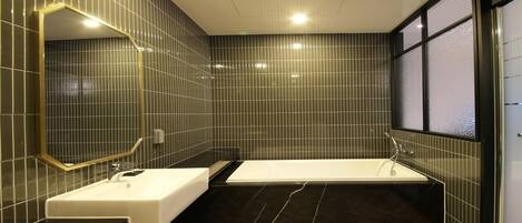 A modern bathroom with a large mirror, a bathtub, and a sink.