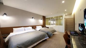 A hotel room with two beds, a desk with a computer, and a TV.