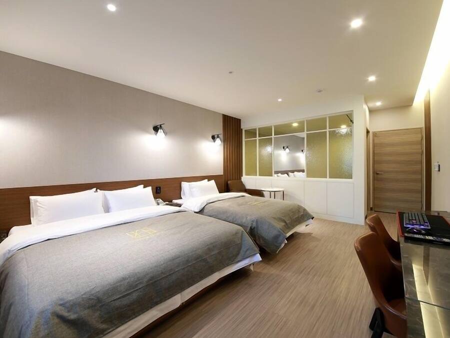 A hotel room with two beds, a desk with a computer, and a TV.