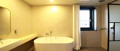 A modern bathroom with a freestanding bathtub, a large mirror, and a window with curtains.