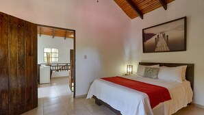 A bedroom with a bed, a wooden door, a window, and a painting on the wall. - Villa Bayacanes (La Vega)