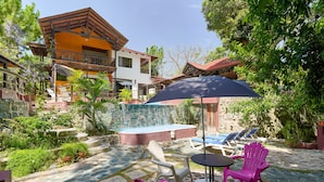 A patio area with outdoor seating, a pool, and a stone wall. - Villa Bayacanes (La Vega)