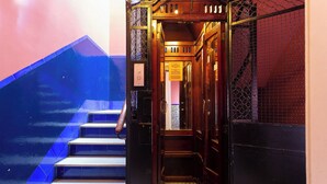 A staircase with a handrail, a wooden door with a sign, and a patterned floor.