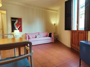 A cozy room with a striped sofa, a small table with a lamp, a chair, and a cabinet.