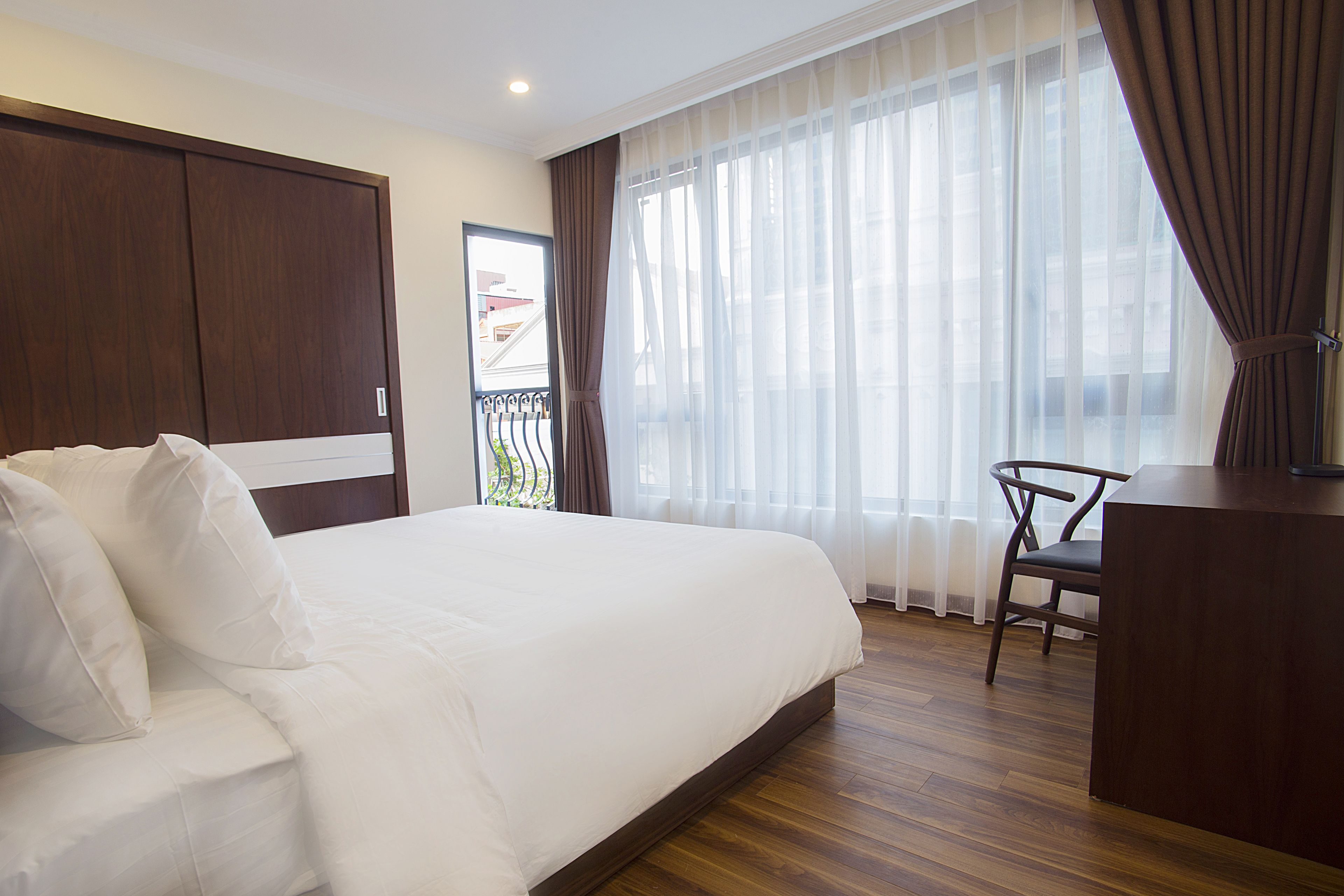 A hotel room with a large bed, a desk, and a chair.
