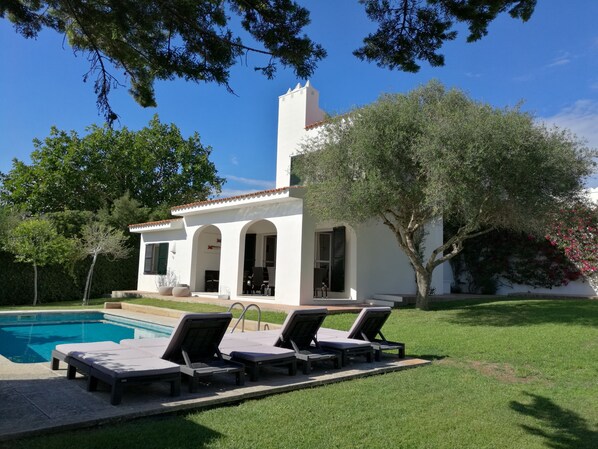A white villa with a swimming pool, outdoor seating, and a garden. - 4 bedrooms Villa with pool, Sea view - 3 min walk to Binibeca vell (Binibequer)